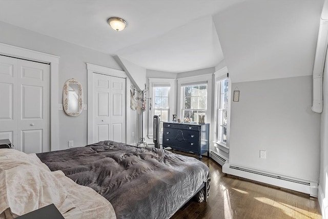 bedroom featuring two closets, dark wood-type flooring, and a baseboard radiator