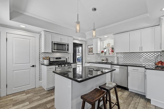 kitchen with a center island, decorative light fixtures, stainless steel appliances, light hardwood / wood-style floors, and white cabinetry