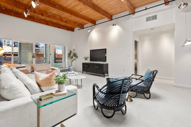 carpeted living room with beamed ceiling, a high ceiling, and wooden ceiling