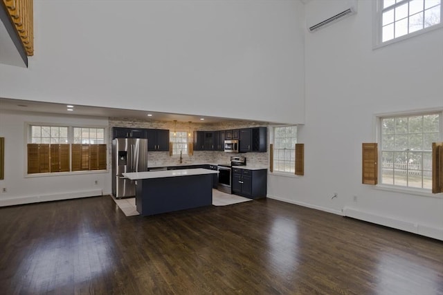 16 Poole Rd, Belchertown, MA 01007 - kitchen featuring a towering ceiling, a center island, light countertops, stainless steel appliances, and a wall mounted air conditioner