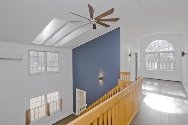 16 Poole Rd, Belchertown, MA 01007 - hall with baseboards, an upstairs landing, a wall unit AC, lofted ceiling with skylight, and wood finished floors