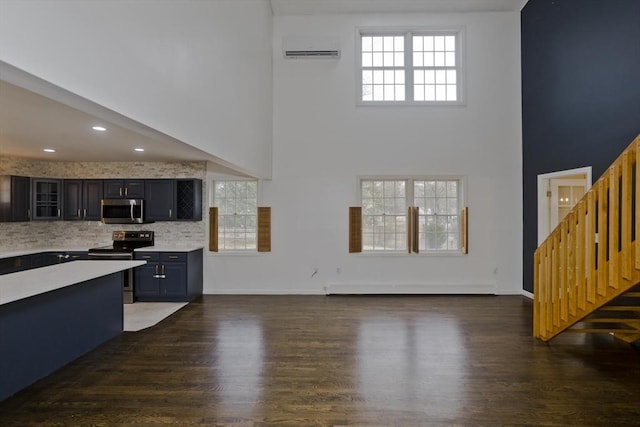 16 Poole Rd, Belchertown, MA 01007 - kitchen with glass insert cabinets, a wall mounted AC, appliances with stainless steel finishes, wood finished floors, and light countertops