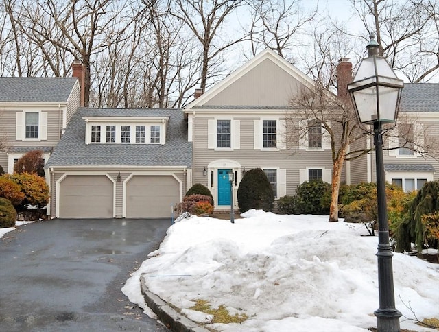 view of front of home featuring aphalt driveway, a shingled roof, and a chimney