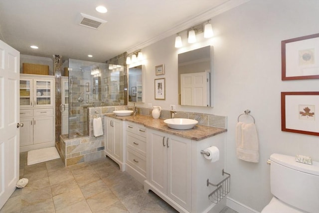 full bathroom featuring toilet, a shower stall, ornamental molding, and a sink