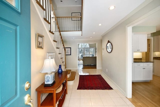 foyer entrance featuring stairway, baseboards, ornamental molding, and light tile patterned flooring