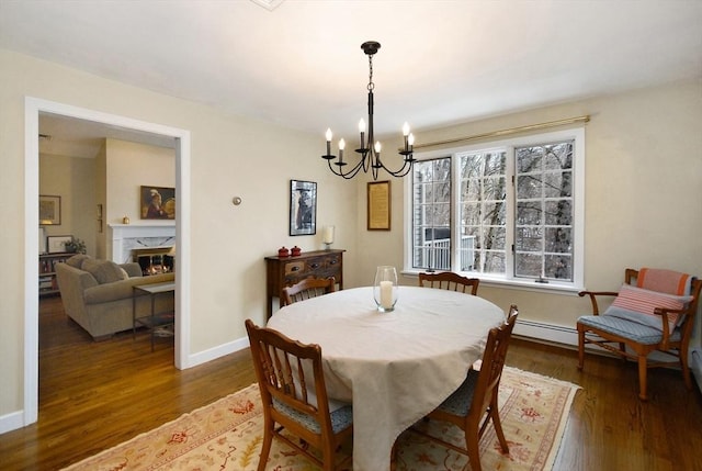 dining space featuring baseboards, a notable chandelier, a premium fireplace, and wood finished floors