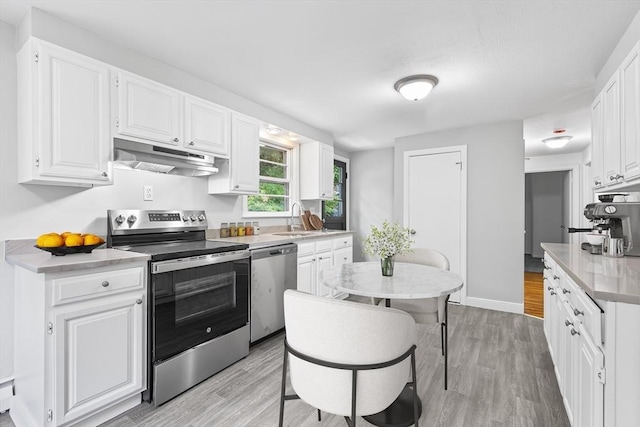 9 Margaret St, Burlington, MA 01803 - kitchen with appliances with stainless steel finishes, under cabinet range hood, light wood-style floors, white cabinetry, and light countertops