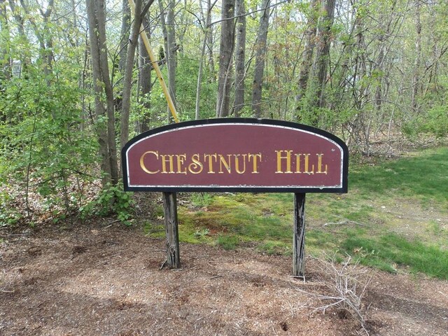 community / neighborhood sign with a view of trees