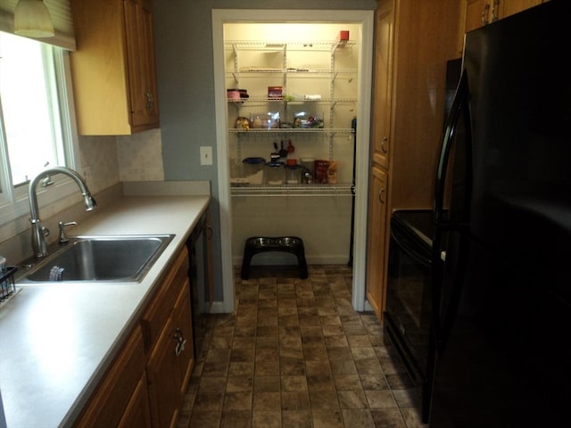 kitchen with black appliances, light countertops, brown cabinets, and a sink
