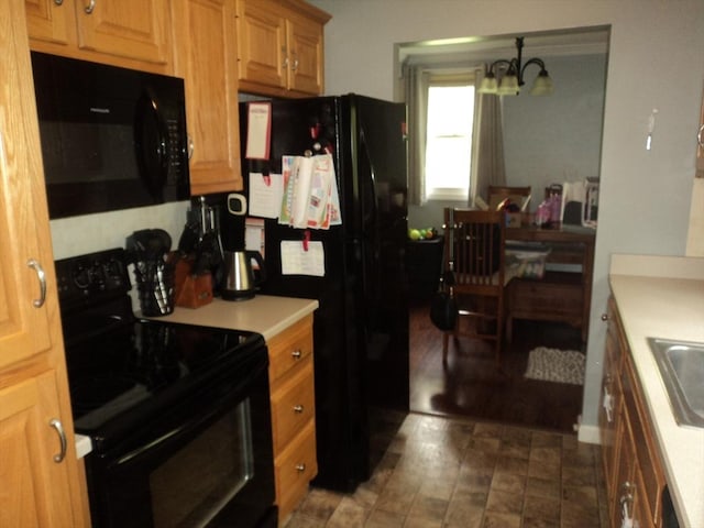 kitchen featuring black appliances, light countertops, a chandelier, and a sink