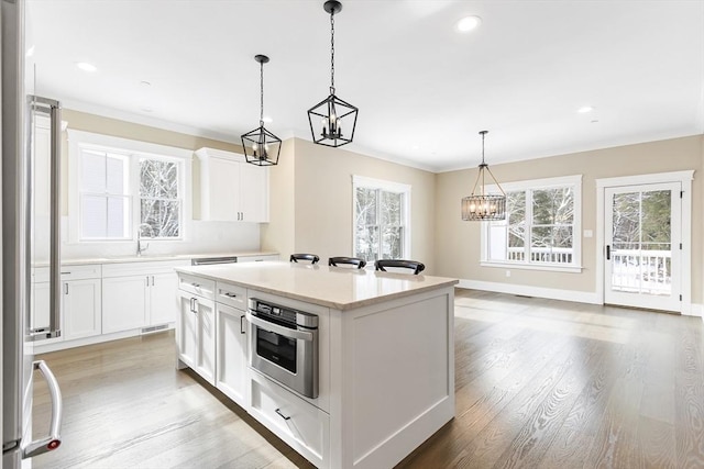 30 Southfield Ln Unit 30, Sherborn, MA 01770 - kitchen with stainless steel oven, a chandelier, a sink, light wood-style flooring, and a kitchen island