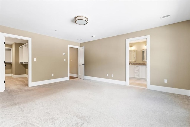 30 Southfield Ln Unit 30, Sherborn, MA 01770 - unfurnished bedroom featuring light carpet, a walk in closet, baseboards, and connected bathroom