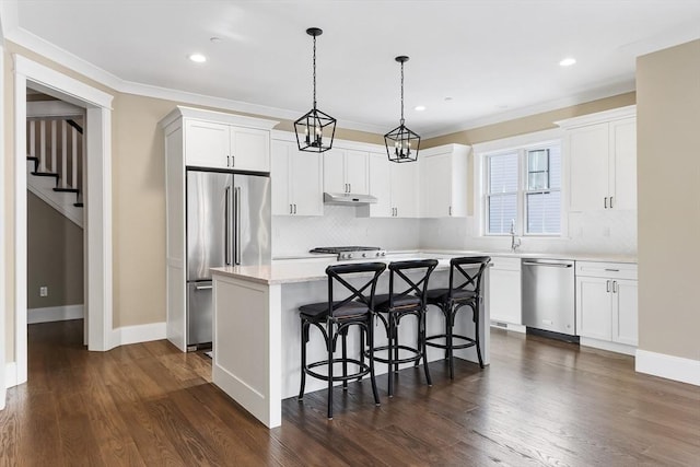 30 Southfield Ln Unit 30, Sherborn, MA 01770 - kitchen featuring appliances with stainless steel finishes, a kitchen island, backsplash, a kitchen breakfast bar, and white cabinetry