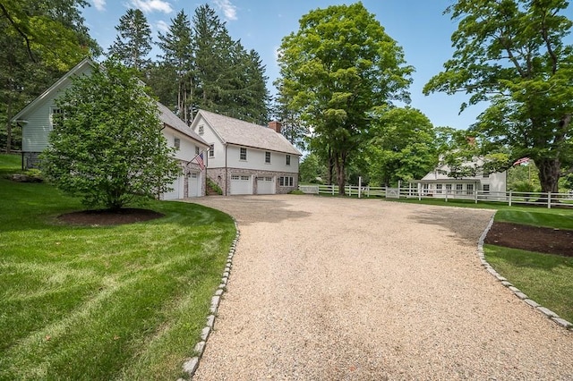 view of front of home with a chimney, fence, an attached garage, driveway, and a front yard