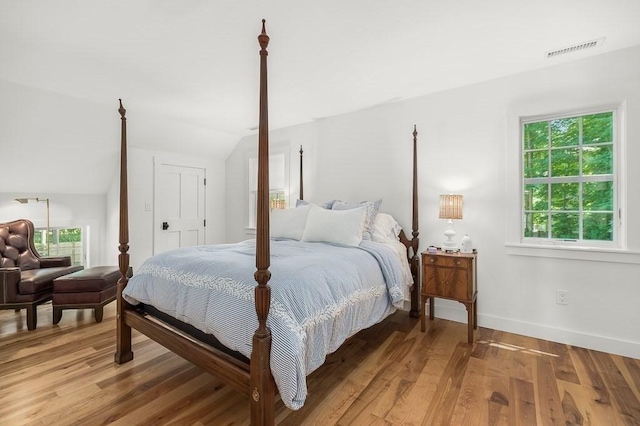 bedroom featuring lofted ceiling, light wood-style floors, visible vents, and baseboards