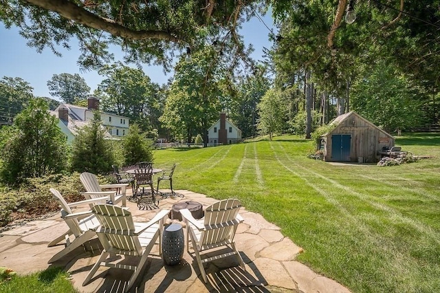 view of yard with a shed, an outdoor fire pit, an outdoor structure, and a patio