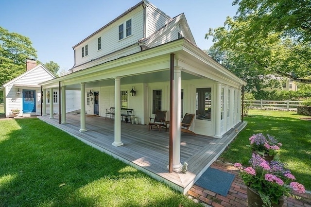 rear view of property featuring fence and a lawn