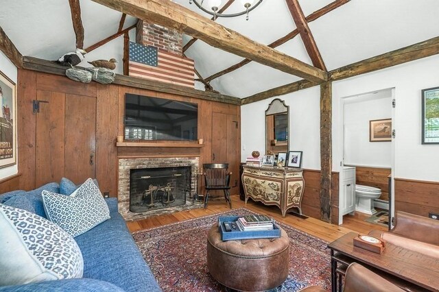 living room with wainscoting, a fireplace, wood finished floors, and beam ceiling