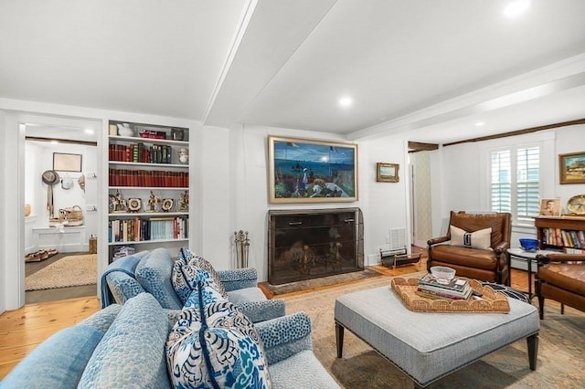 living area featuring wood finished floors, a fireplace with flush hearth, built in features, ornamental molding, and recessed lighting