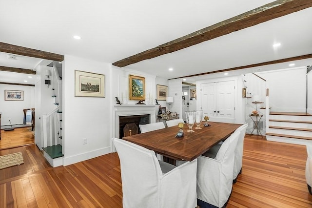 dining room with stairway, beam ceiling, baseboards, and wood finished floors