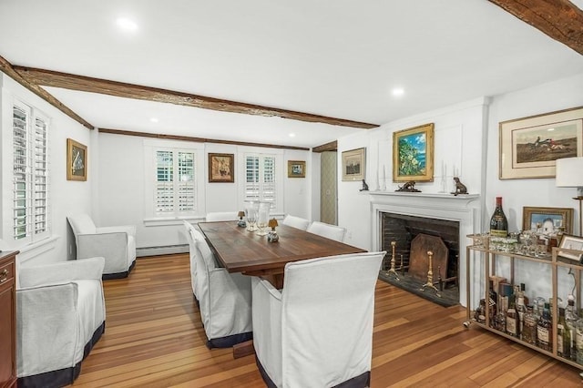 dining room featuring a baseboard heating unit, a fireplace with flush hearth, recessed lighting, beamed ceiling, and wood finished floors