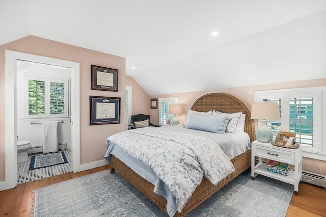 bedroom with vaulted ceiling, wood finished floors, and multiple windows