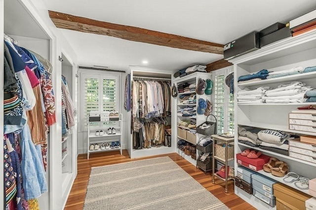 walk in closet with beam ceiling and wood finished floors