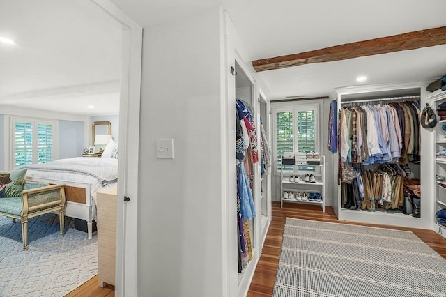 walk in closet featuring wood finished floors and beam ceiling