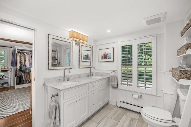 bathroom featuring a baseboard heating unit, a healthy amount of sunlight, and a sink