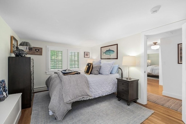 bedroom featuring a baseboard heating unit and wood finished floors