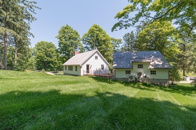 back of property with a chimney, a yard, and a deck