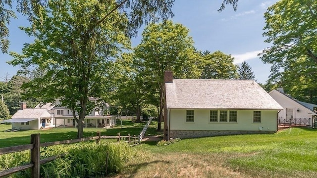 view of home's exterior with fence, a lawn, and a chimney