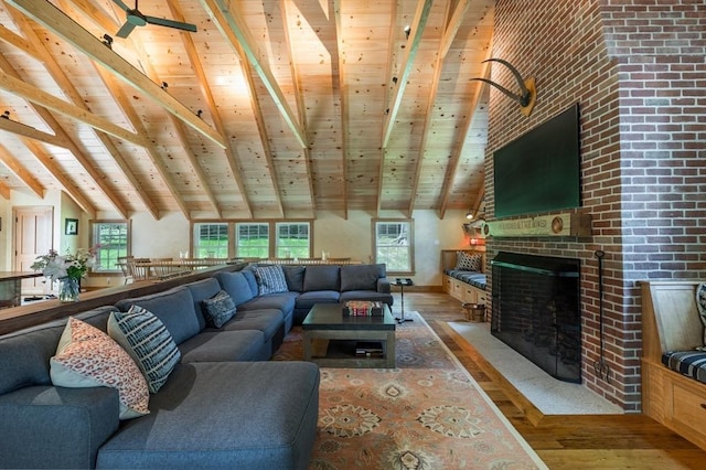 living area with hardwood / wood-style floors, wooden ceiling, beam ceiling, a wealth of natural light, and a fireplace