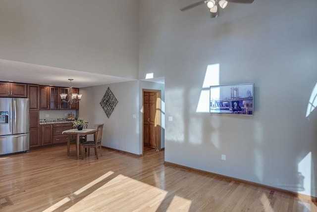 interior space featuring a towering ceiling, ceiling fan with notable chandelier, and light hardwood / wood-style flooring