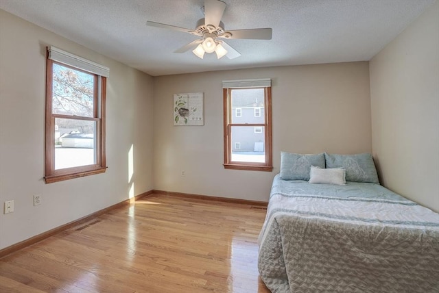 bedroom featuring a textured ceiling, light hardwood / wood-style flooring, and ceiling fan