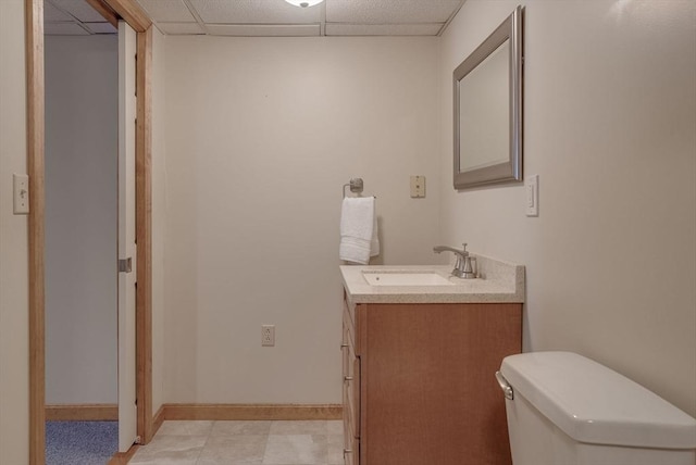 bathroom featuring vanity, toilet, and a drop ceiling