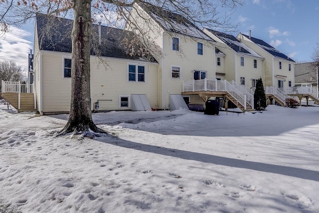 snow covered rear of property with a deck