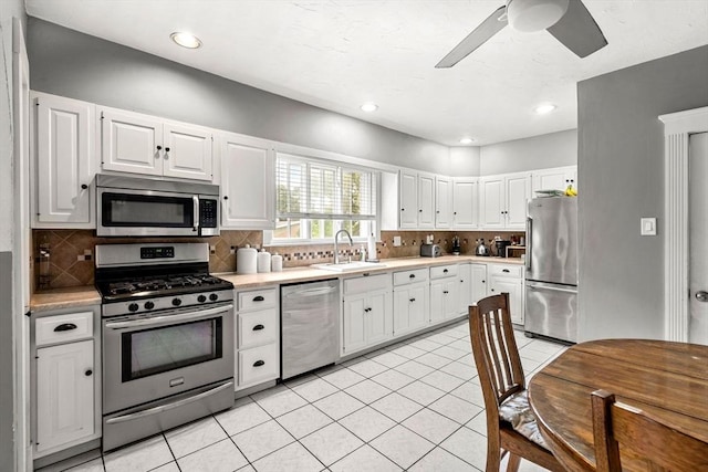 26 Enfield Rd, Winthrop, MA 02152 - kitchen with stainless steel appliances, light countertops, a ceiling fan, decorative backsplash, and white cabinetry
