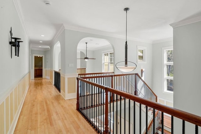 corridor featuring a wealth of natural light, arched walkways, light wood-type flooring, and an upstairs landing