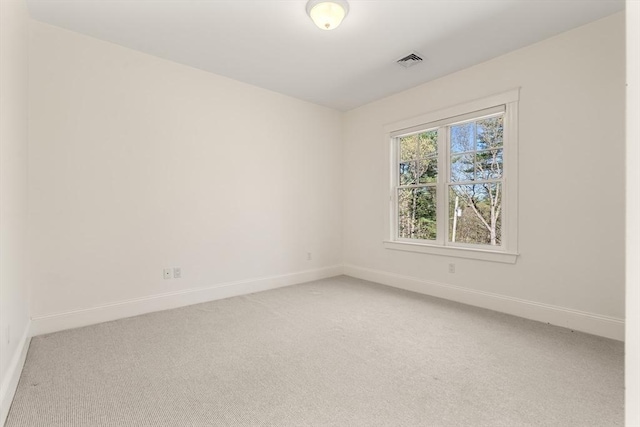 spare room with light colored carpet, baseboards, and visible vents