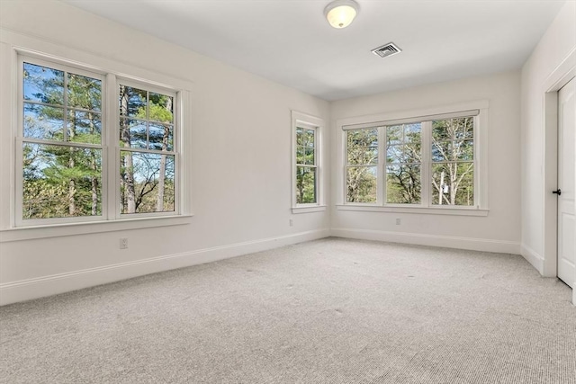spare room with carpet floors, baseboards, plenty of natural light, and visible vents