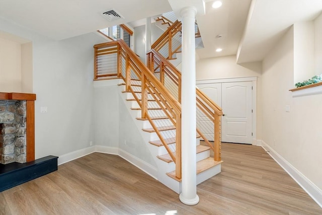 staircase featuring baseboards, a fireplace, visible vents, and wood finished floors