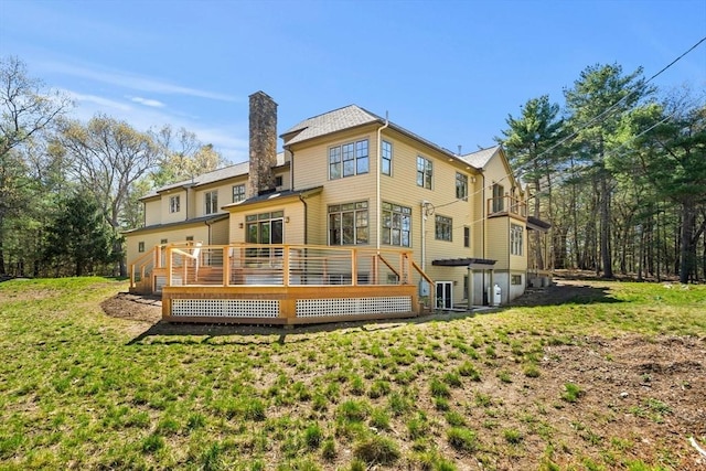 rear view of property with a chimney, a deck, and a yard