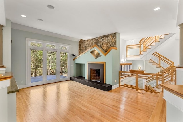 unfurnished living room featuring recessed lighting, baseboards, stairs, hardwood / wood-style flooring, and a large fireplace