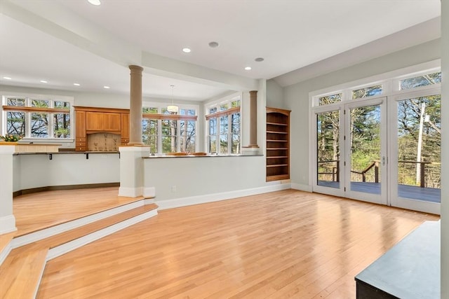 unfurnished living room featuring a wealth of natural light, light wood-style flooring, decorative columns, and recessed lighting