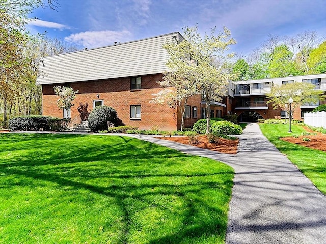 rear view of property with brick siding and a lawn