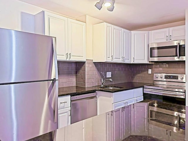 kitchen featuring stainless steel appliances, white cabinets, decorative backsplash, and a sink