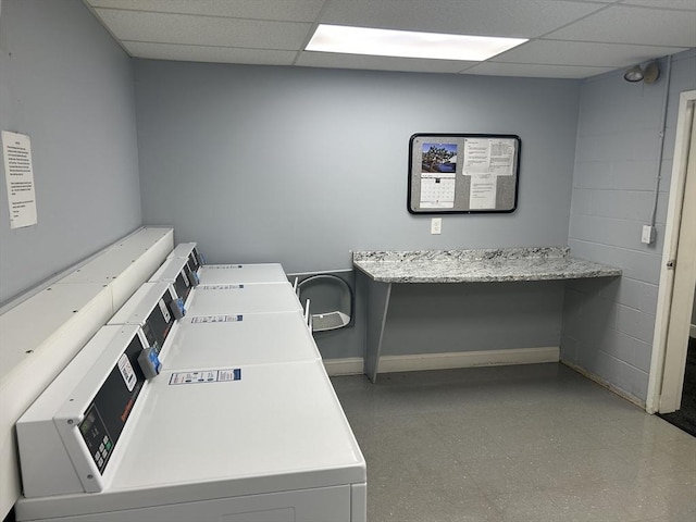 community laundry room featuring washer and dryer, light floors, and baseboards