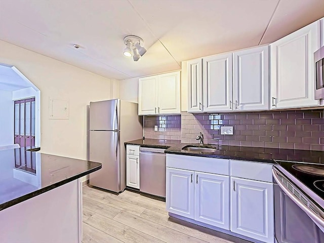 kitchen with dark countertops, white cabinetry, stainless steel appliances, and a sink