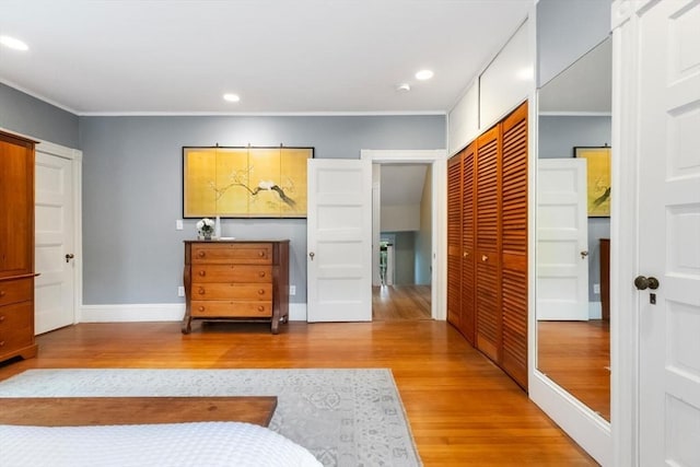 bedroom with wood finished floors, crown molding, a closet, recessed lighting, and baseboards